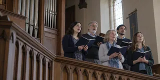 Scène contemporaine imaginée : cinq adultes chantent dans une tribune d’église.