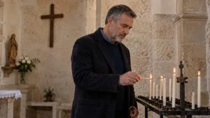 Un homme allume une petite bougie dans une église.